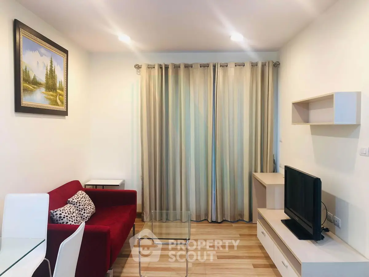 Modern living room with red sofa, glass coffee table, and wall-mounted TV in a cozy apartment.