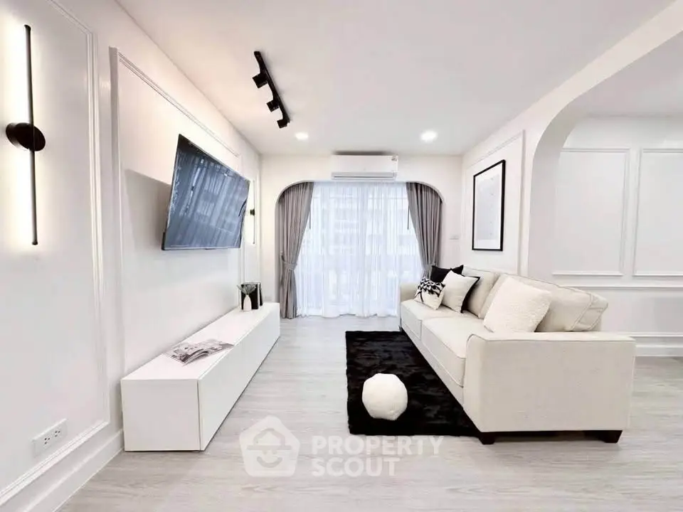Modern living room with sleek design, featuring a wall-mounted TV, stylish sofa, and elegant decor.