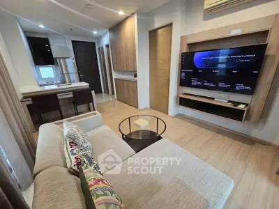 Modern living room with open kitchen, featuring sleek furniture and a wall-mounted TV, perfect for urban living.
