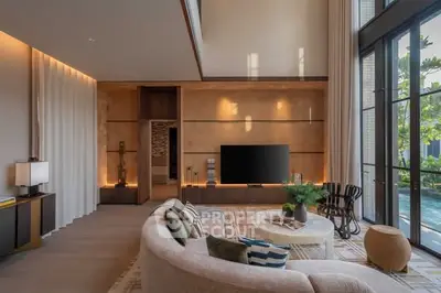 Luxurious living room with modern decor and large windows overlooking a pool.