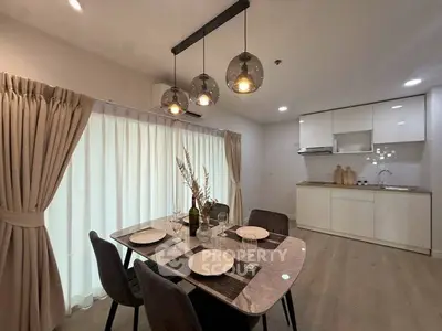 Modern dining area with elegant lighting and open kitchen layout in a stylish apartment.