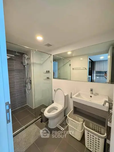 Modern bathroom with glass shower, sleek fixtures, and ample storage space.