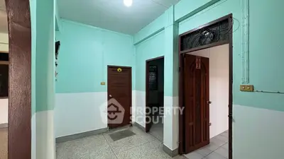 Spacious interior hallway with multiple wooden doors and mint green walls.