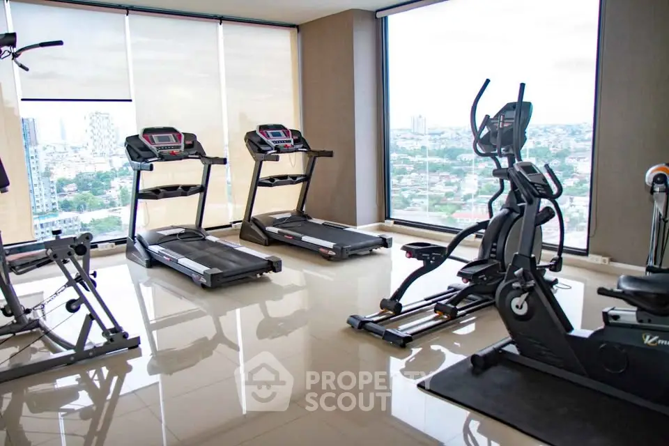 Modern gym with city view featuring treadmills and exercise equipment in high-rise building.