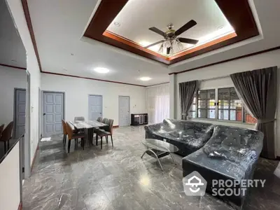 Spacious living room with modern furniture and ceiling fan, ideal for family gatherings.