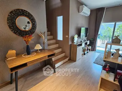 Stylish living room with modern decor and natural light, featuring a staircase and balcony access.