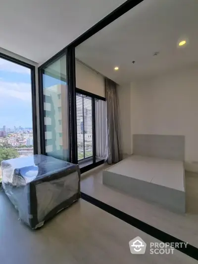 Modern bedroom with large windows and city view in high-rise apartment