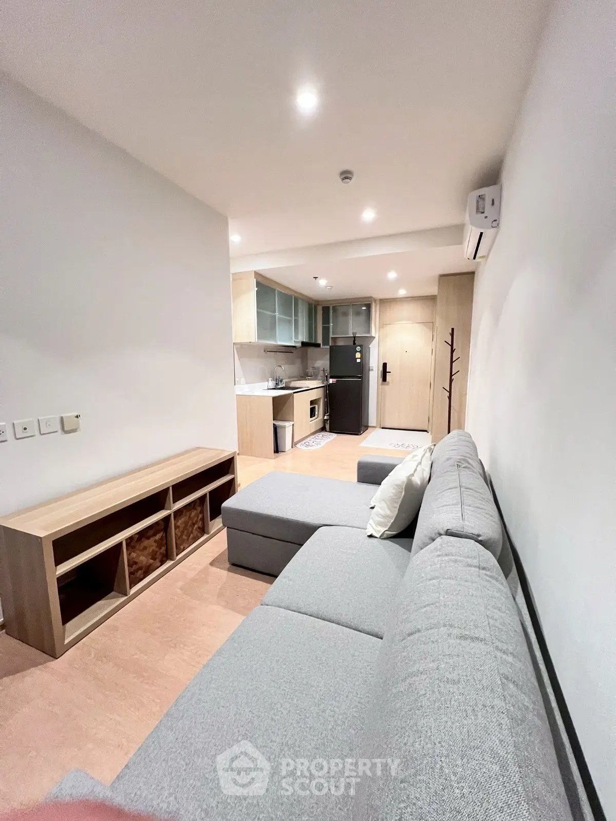 Modern open-layout living room with sleek kitchen and cozy gray sofa.