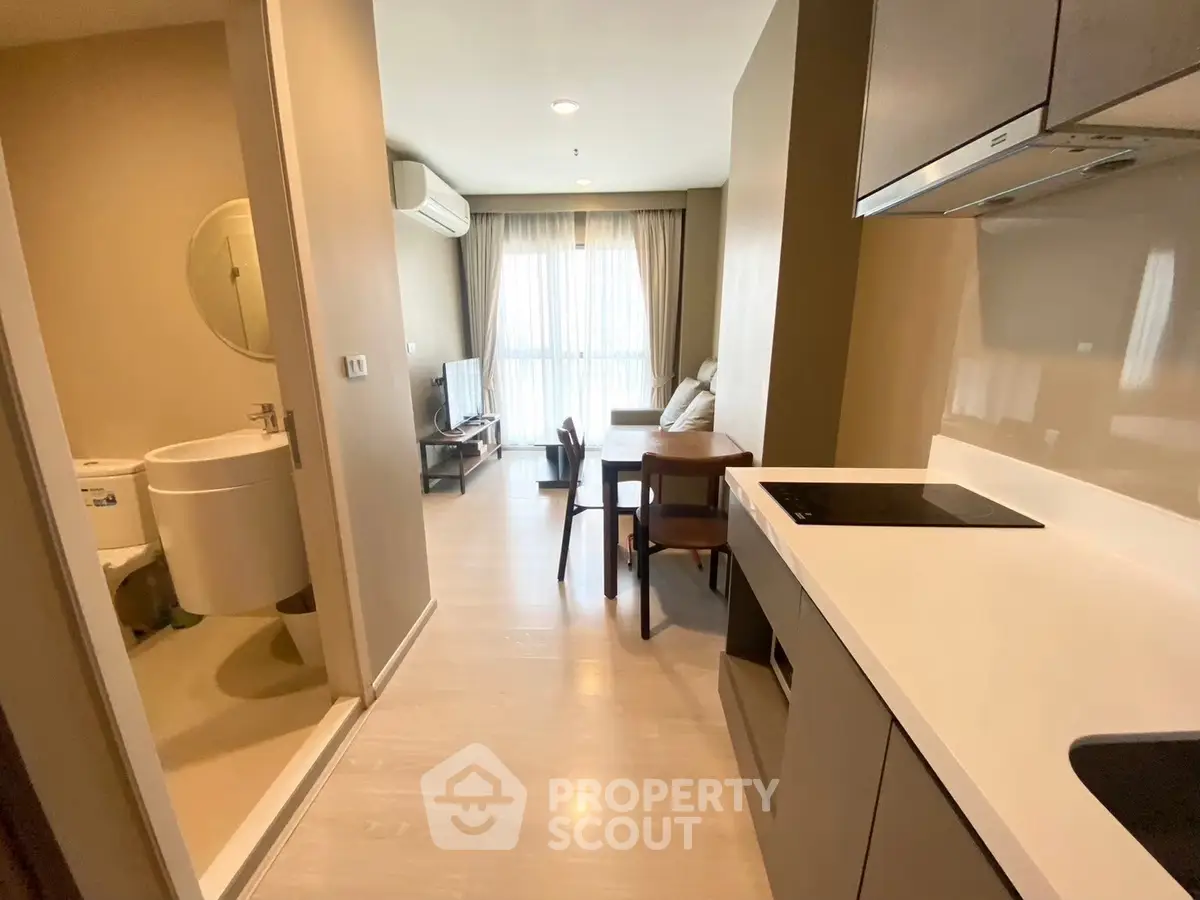 Modern open-plan apartment with kitchen and living area, featuring sleek design and natural light.
