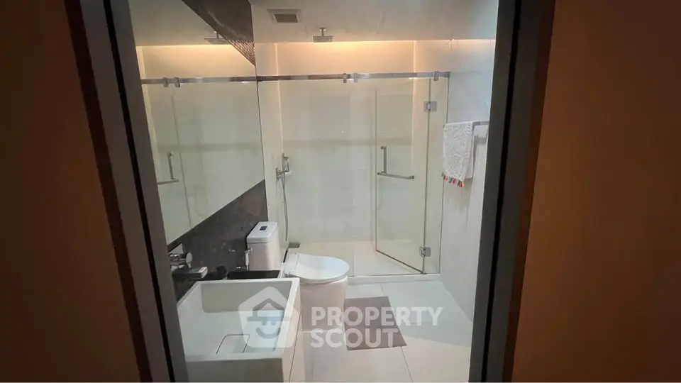 Modern bathroom with glass shower and sleek fixtures in contemporary apartment.