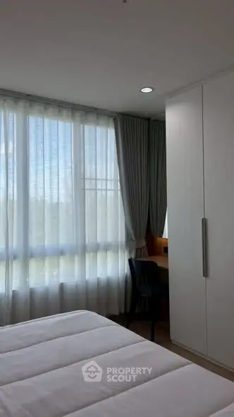 Bright bedroom with large window and modern furniture