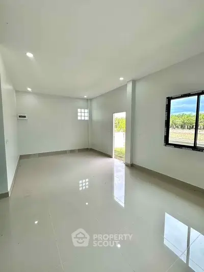Spacious empty living room with glossy tiled floors and large window offering natural light.