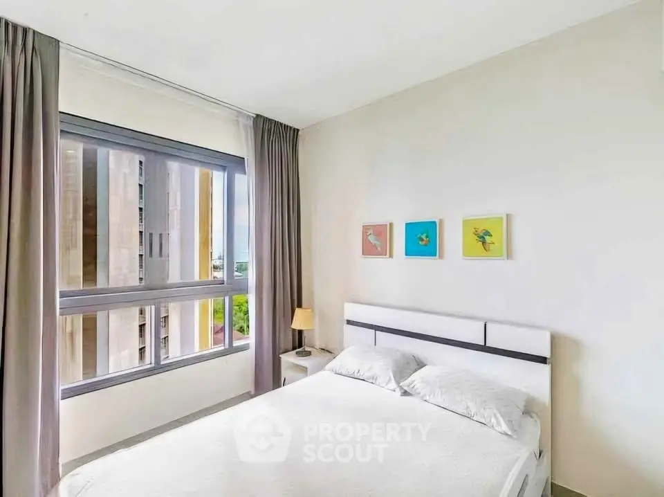 Bright bedroom with large window and modern decor in high-rise apartment.