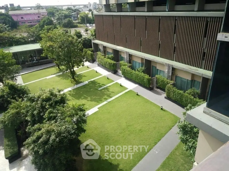 Lush green garden space in a modern residential complex, showcasing manicured lawns and contemporary architecture for serene urban living.