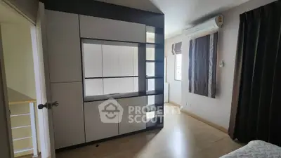 Modern bedroom with sleek built-in storage and air conditioning, featuring minimalist design and natural light.