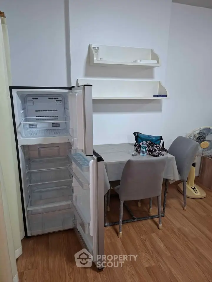 Cozy dining area with open fridge and modern decor, perfect for small apartments.