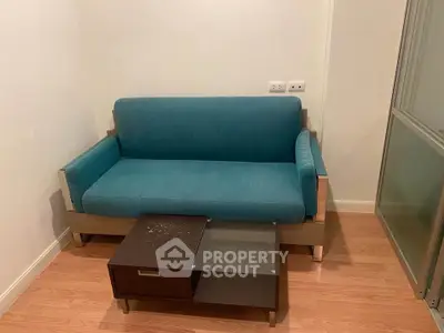 Cozy living room with modern teal sofa and sleek coffee table on wooden flooring.