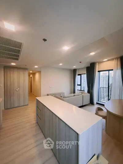Spacious modern living room with open layout and city view, featuring elegant furnishings and natural light.