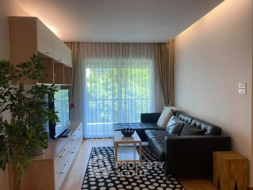 Modern living room with sleek furniture and large window offering natural light.