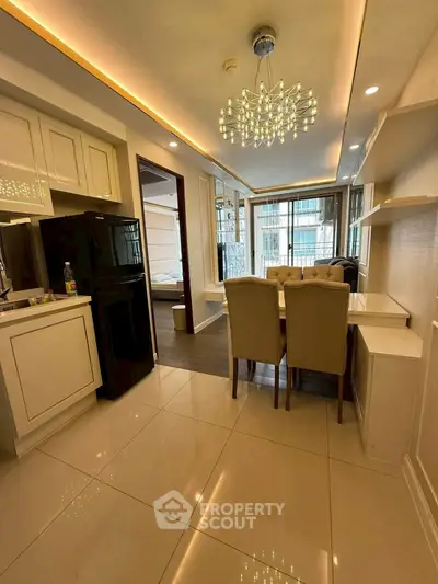 Elegant open-layout kitchen and dining area with modern chandelier and sleek design.
