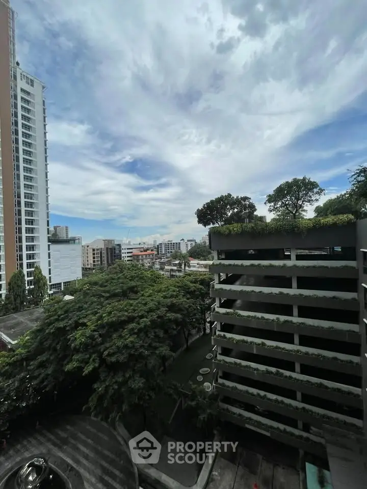 Stunning cityscape view from high-rise building with lush greenery and modern architecture.
