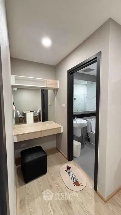 Modern apartment with stylish vanity area and adjacent bathroom, featuring sleek design and contemporary fixtures.
