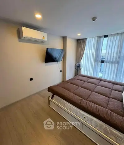 Modern bedroom with large window and wall-mounted TV in a stylish apartment.