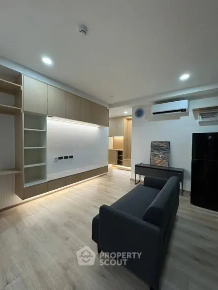 Modern living room with sleek furniture and built-in storage, featuring a minimalist design.