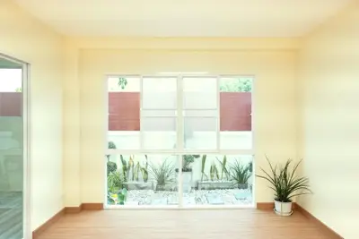 Bright and airy room with large window overlooking a modern garden, perfect for relaxation.