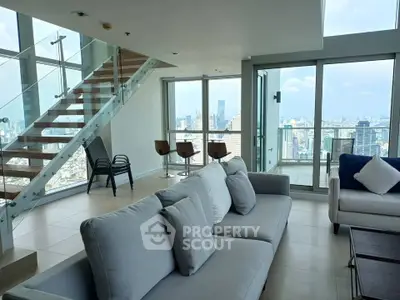 Luxurious modern living room with stunning city view and elegant staircase in high-rise apartment.