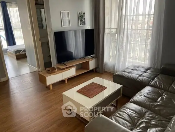 Modern living room with sleek furniture and large TV, featuring a cozy atmosphere and natural light.
