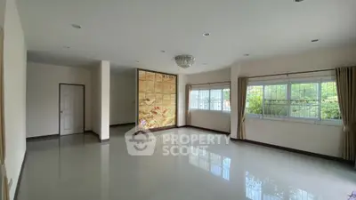 Spacious living room with large windows and elegant chandelier, offering abundant natural light and serene garden views.