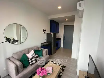 Modern living room with stylish decor and compact kitchen in open layout apartment.
