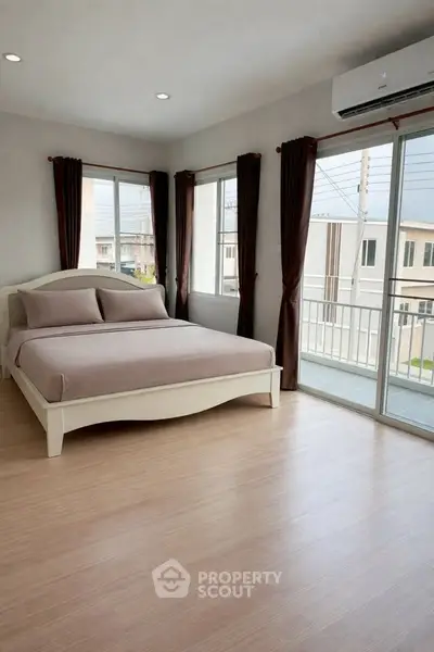 Spacious bedroom with large windows and balcony access in modern apartment.