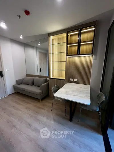 Modern living room with stylish sofa and dining area, featuring elegant lighting and wooden flooring.