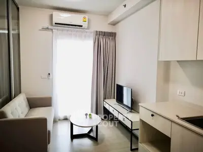 Modern living room with sleek furniture and natural light, featuring a cozy sofa and flat-screen TV.