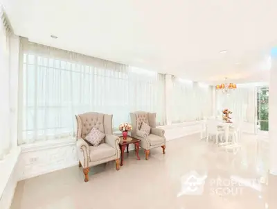 Elegant living room with plush chairs and dining area in bright natural light