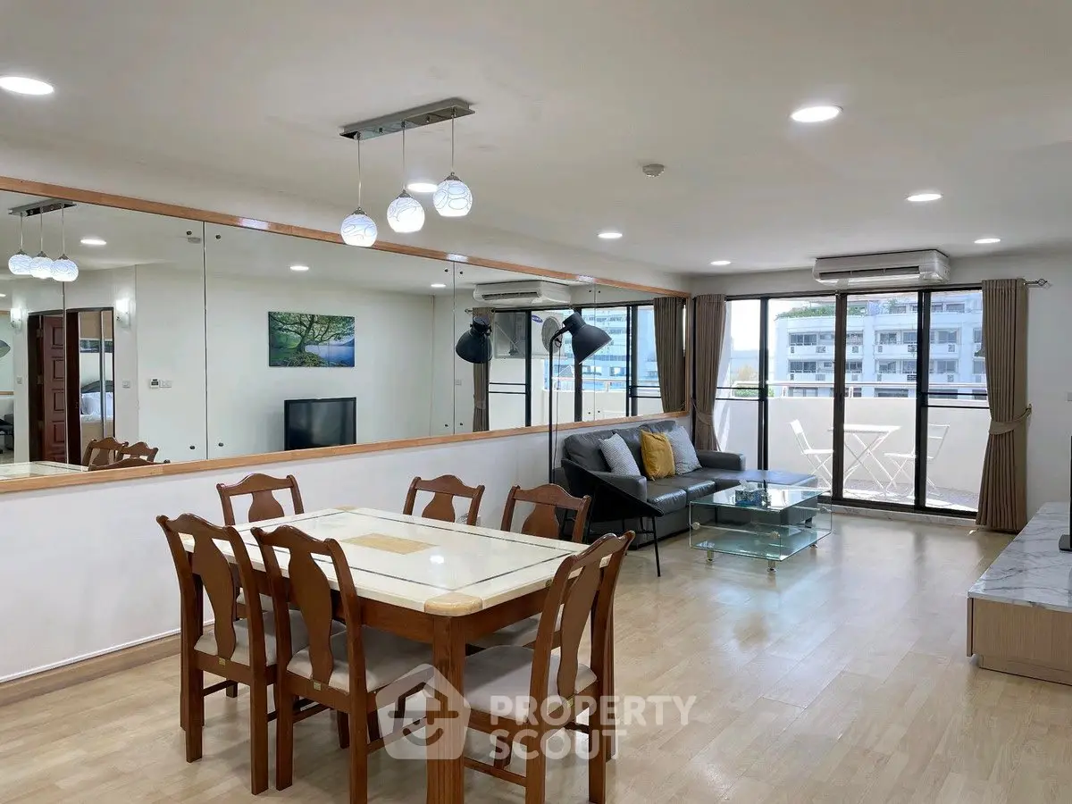 Spacious living room with dining area and balcony view in modern apartment.