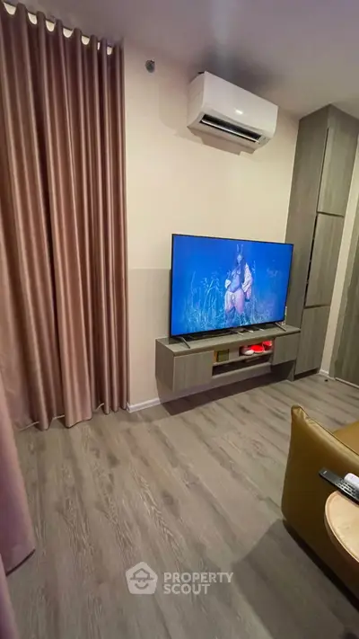 Modern living room with sleek TV setup and air conditioning, featuring elegant curtains and stylish flooring.