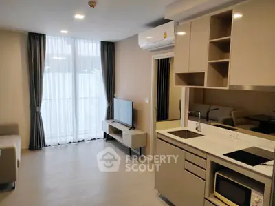 Modern living room with sleek kitchen and large window in stylish apartment.