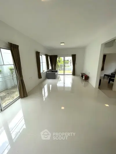 Spacious living room with large windows and modern decor, perfect for natural light lovers.