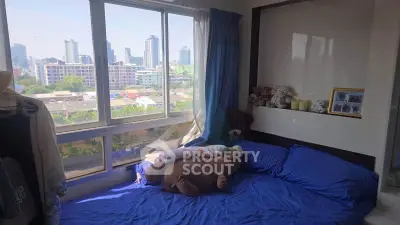 Cozy bedroom with city view, plush bedding, and large windows in urban apartment.