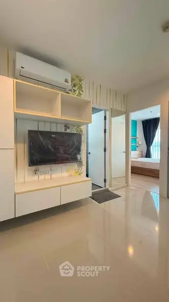 Modern living room with sleek TV setup and view into stylish bedroom