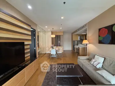 Spacious modern living room with elegant decor and open dining area, featuring wooden flooring and stylish furniture.