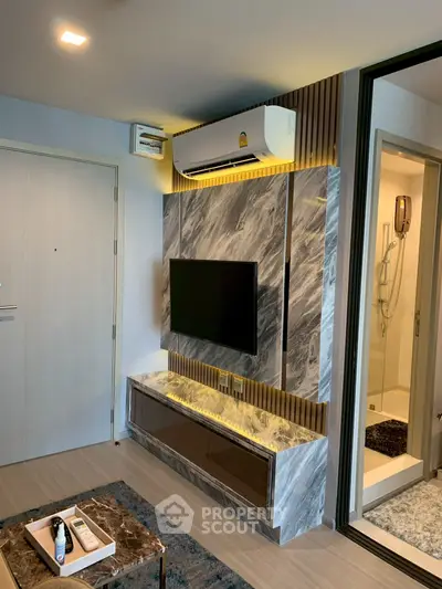 Modern living room with marble TV wall and air conditioning, adjacent to a stylish bathroom.