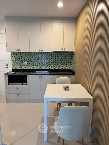 Modern compact kitchen with sleek cabinetry and stylish dining area in a cozy apartment.