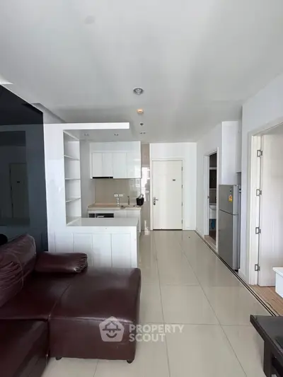 Modern open-layout living room with sleek kitchen and leather sofa, perfect for urban living.