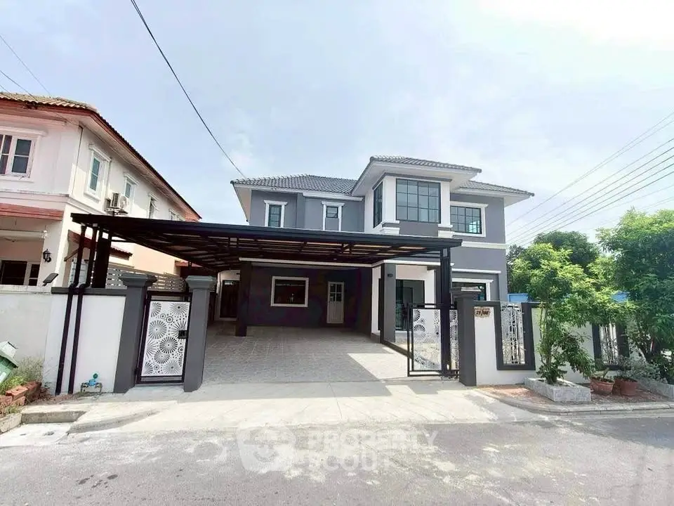 Spacious modern two-story house with gated driveway and elegant facade in a suburban neighborhood.