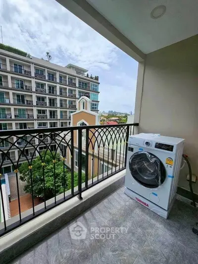 Spacious balcony with washing machine and scenic view of modern apartment complex.