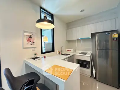 Modern kitchen with sleek design, featuring stainless steel appliances and stylish lighting in a compact space.